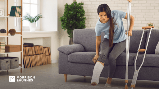Lady with injured leg using crutch to get off couch